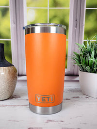 an orange yeti tumbler next to a potted plant