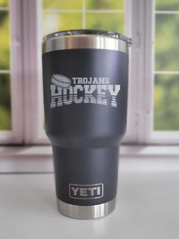 a black and silver yeti cup sitting in front of a window