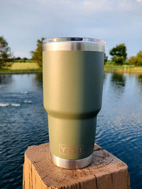 a cup sitting on top of a wooden post next to a body of water