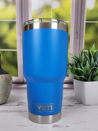a blue yeti cup sitting next to a potted plant