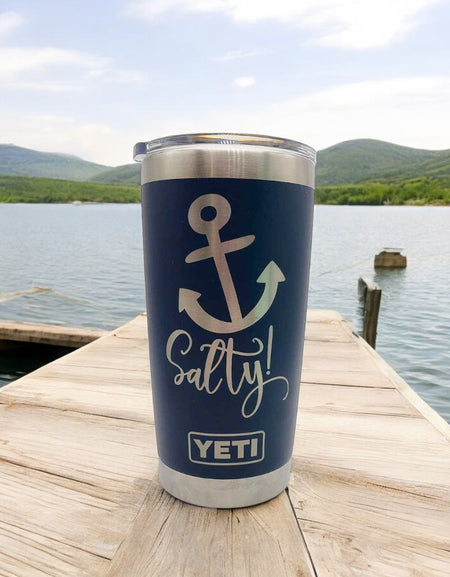 a cup sitting on top of a wooden dock next to a body of water