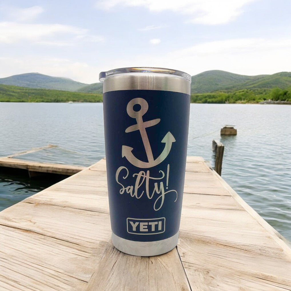 a cup sitting on top of a wooden dock next to a body of water